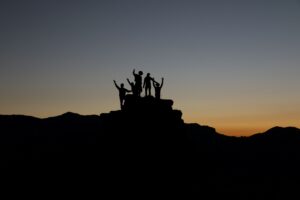 People on a vehicle with arms up cheering at sunset